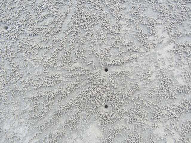 3 buchi astratti nella sabbia con un pizzo attorno
